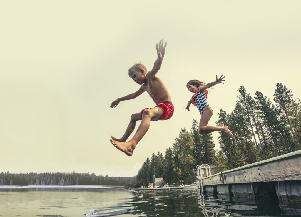 Kids jumping off pier into lake