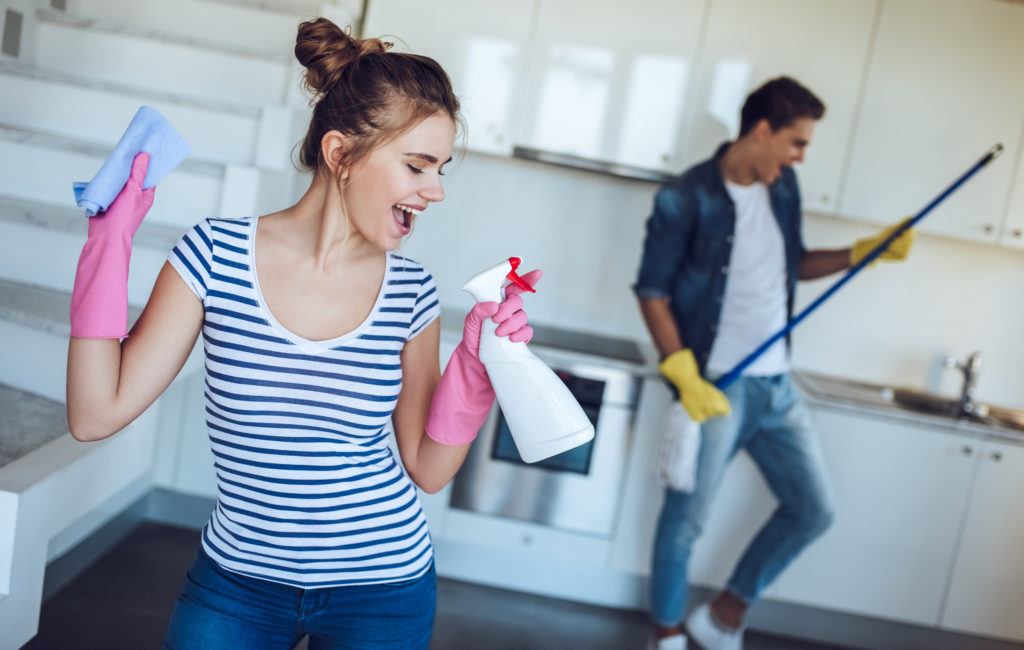 Young happy couple is having fun while doing cleaning at home.