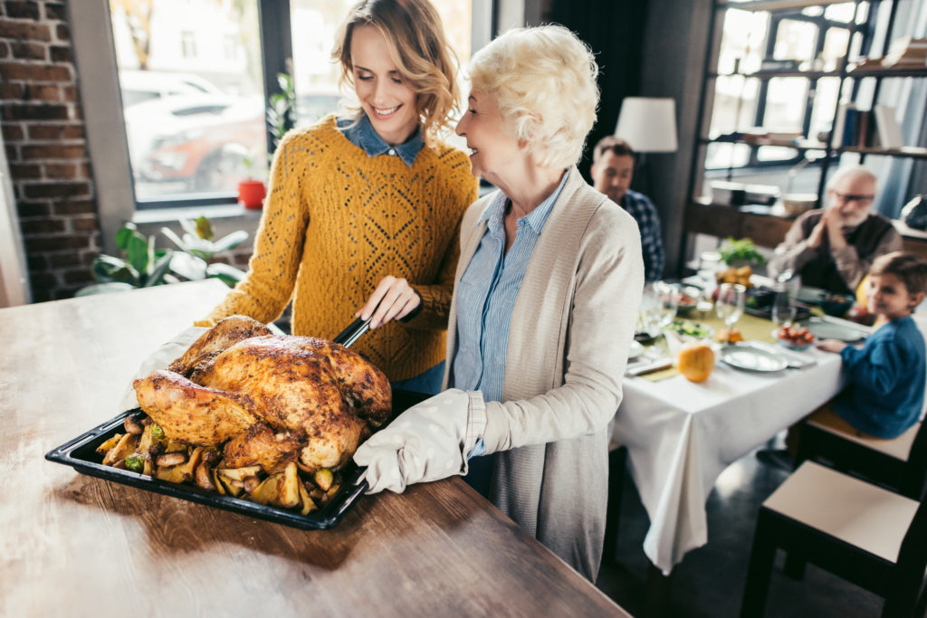 smiling senior mother and daughter with thanksgiving turkey for family dinner