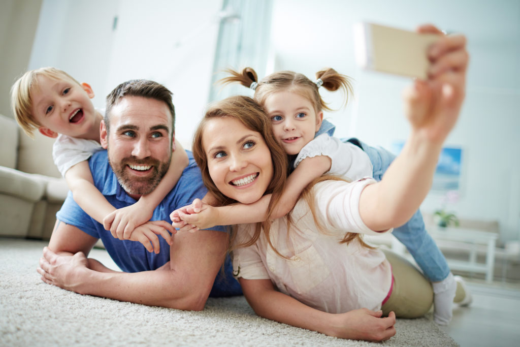 Happy young family taking selfie on the floor at home