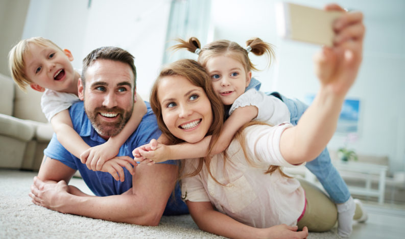Happy young family taking selfie on the floor at home