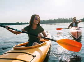 Couple kayaking together. Beautiful young couple kayaking on lake together and smiling