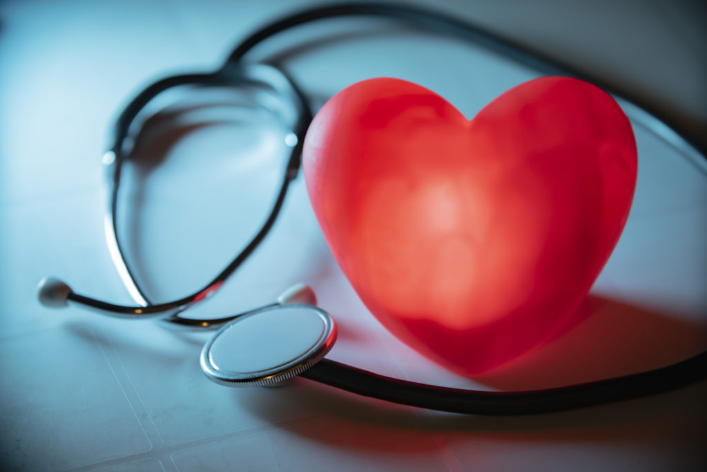 Red heart with stethoscope on blue background. 