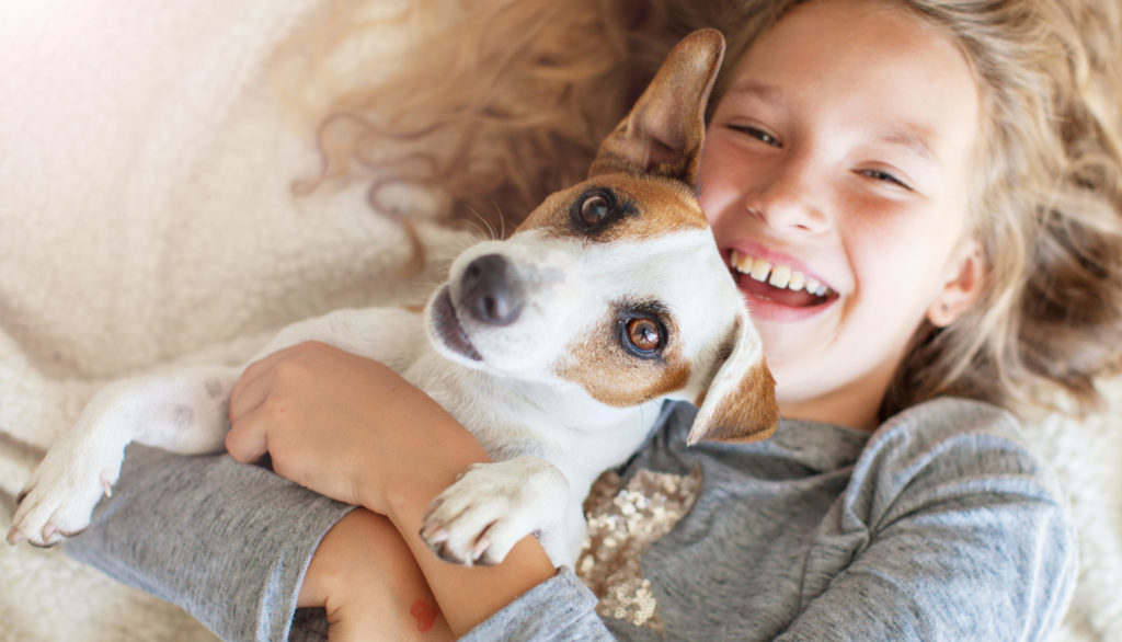 Happy child with dog. Portrait girl with pet. Jack Rassell with teen embracing