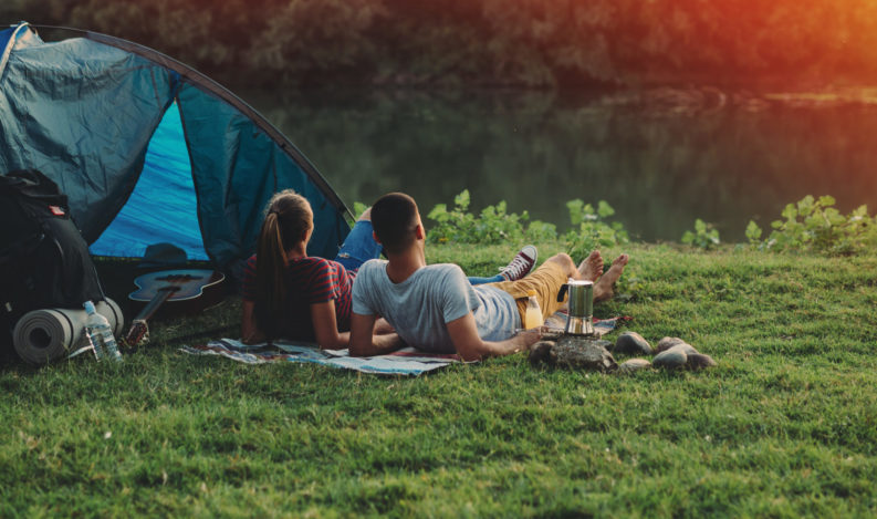 young couple relaxing by the river. camping outdoor